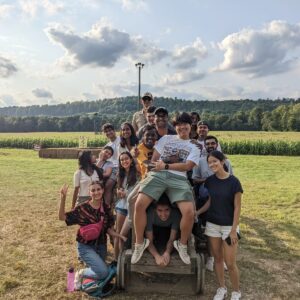 The group of international students gathered on a plain field, posing for a photo.